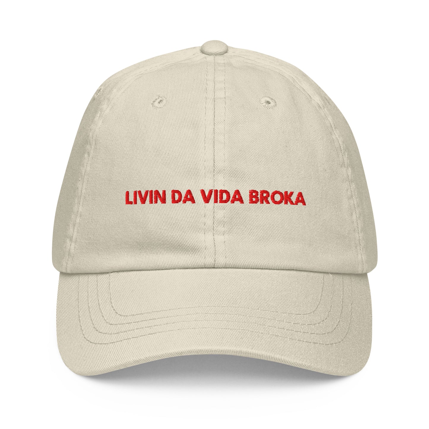 Beige embroidered baseball cap, front view (embroidery mockup currently reads "LIVIN DA VIDA BROKA" — misspelling, pending corrected artwork)